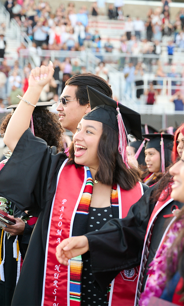 Graduates standing and celebrating during a commencement ceremony.