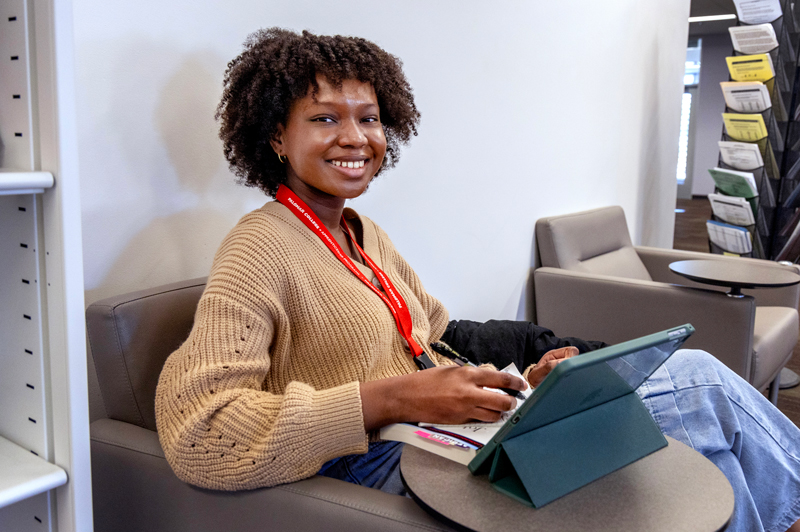 Person sitting indoors using a tablet in a lounge.